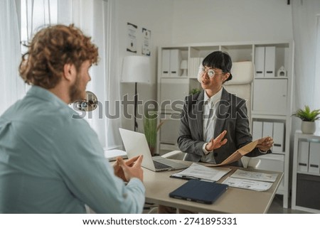 Human resources professional interviewing a potential job candidate in a modern office, discussing employment opportunities and evaluating qualifications during a recruitment process