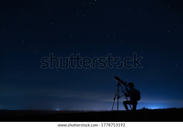 Human silhouette and telescope, a woman looks\
through a telescope at the starry sky. Night sky, stars, long\
exposure, astronomy
