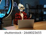 Human skeleton model with laptop at table in dark podcaster