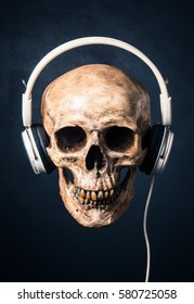 human skull listening with headphones on art dark background