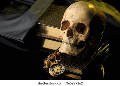 human skull on a book next to the clock. concept of black magic
