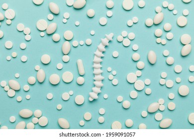 Human Spine Model With Pills On Blue Background.