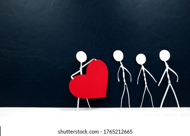 Human stick figure holding a big red heart in dark background. Help, spread love, charity and kindness at times of darkness concept.