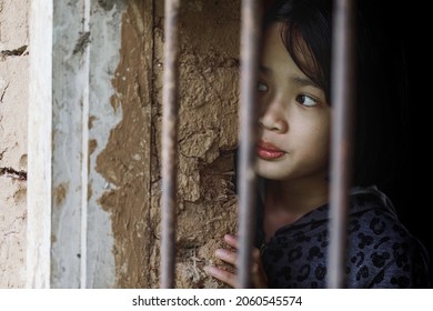 Human Trafficking And Fear Child Concept. Little Girl Hopeless In The Cage. 