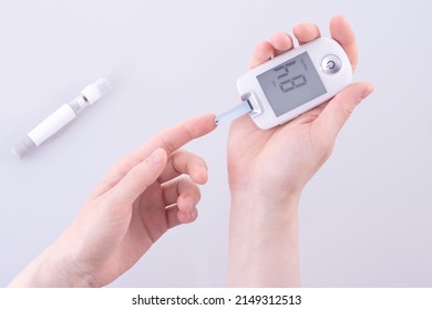 Human using a glucometer to measure and test blood glucose levels from a finger.