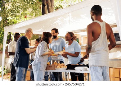 Humanitarian aid group assists in the distribution of contributions to people in need at a homeless and refugee shelter. Volunteers serve meals and provide help through a non-profit food bank.