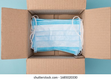 Humanitarian Aid Help Concept. Top Above Overhead Close Up View Photo Of Open Unpacked Unwrapped Box With Lot Of Medical Masks On Blue Background