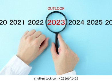 Human's hand  focused on 2023 with OUTLOOK word with magnifying glass - Shutterstock ID 2216641435