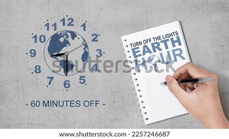 Humans hand write something in a notebook. Earth Hour Concept