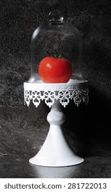 The Humble Tomato In Vintage Cake Stand Against Dark Slate Kitchen Bench Top. 