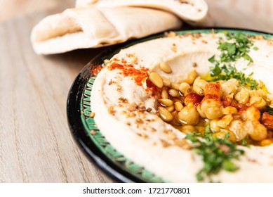 Hummus dish with chickpeas with coriander leaf in a wooden table - Shutterstock ID 1721770801