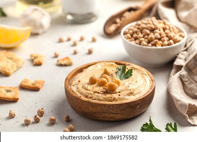 Хумус в деревянной тарелке с петрушкой и гренками. Блюда из нута, вегетарианское блюдо.