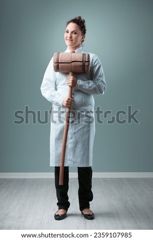 Humorously exaggerating, a scientist in a white coat, inside a blue-green room, swings a 20 KG wooden hammer. It symbolizes the potential danger of not upholding rigorous, independently verified scien