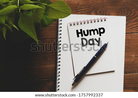 HUMP DAY text written in an office notebook on a wooden table.