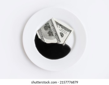 A Hundred Dollar Bill Lies In A White Plate Next To Oil. The Concept Of Petrodollars, The Extraction Of Resources And Their Prices On The Stock Exchange. Embargo And Fuel Crisis. The Price Of Energy.