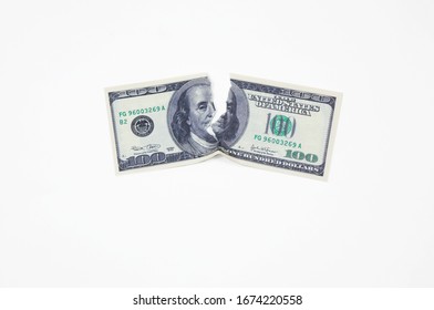 a hundred dollar bill torn in half on a white background top view