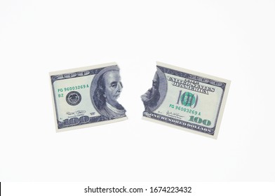 a hundred dollar bill torn in two halves on a white background top view