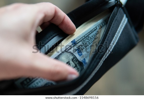 hundred dollar bills are in the wallet. Man\'s hands\
divide dolar bills