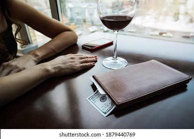 A Hundred Dollars Generous Tip On The Table In A Leather Folder. The Girl Drank The Wine And Paid The Bill. A Large Wine Glass On The Table In An Expensive Restaurant. The Girl Is Waiting For Waiter.