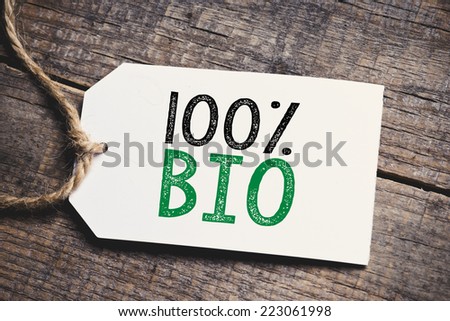 Hundred percent Bio inscription. Green and black inscription hundred percent Bio on blank tags on wooden table 