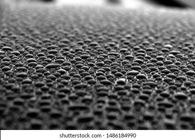 hundreds and thousands of beaded water droplets on a gloss black surface