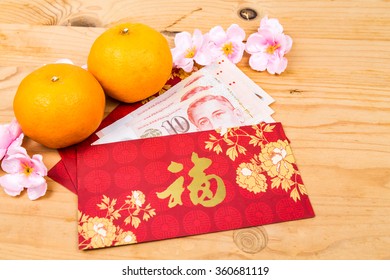 Hung Bao or red packet with Good Fortune Chinese character filled with Singapore Dollar currency, displayed with mandarin oranges