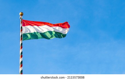 Hungarian flag or flag of Hungary waving against blue sky, space for text