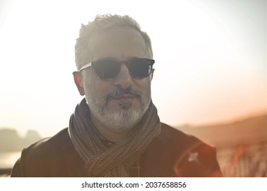 A Hungarian Man With Black Shades Against A Bright Sunset Background