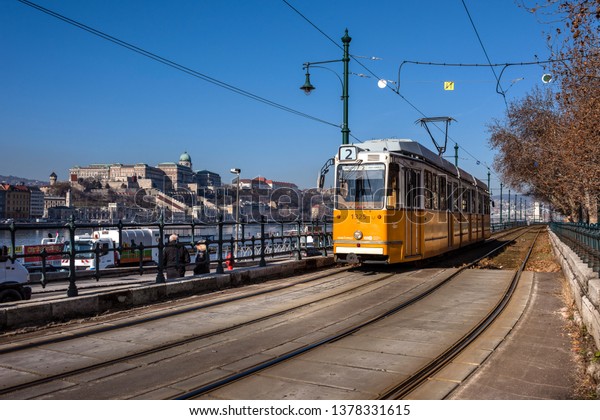 Hungary, Budapest: Street view with famous historic\
orange tram cable car in the city center of the Hungarian capital\
with cityscaepe and blue sky in the background - travel transport.\
Feb 06, 2019