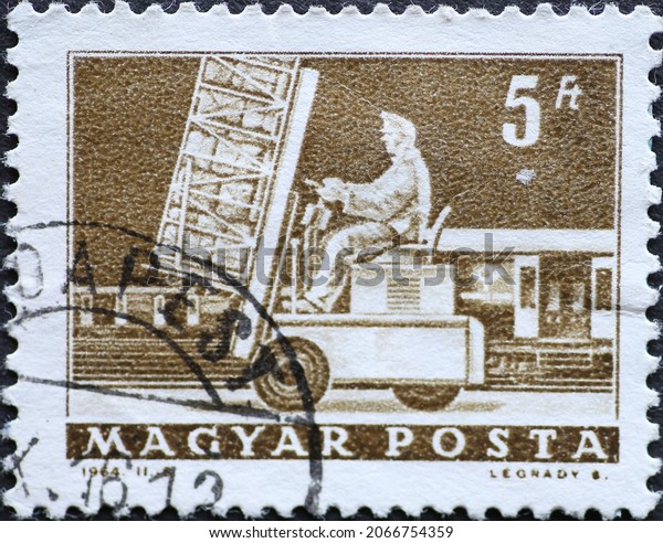 Hungary circa 1964: A post stamp printed in Hungary\
showing a man on a loaded forklifter Hydraulic lift truck  and mail\
car 
