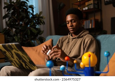Hungry african american dark skinned man pausing a movie or TV show that he was watching, taking off his headphones to take a break or attend to something else. - Shutterstock ID 2364975327