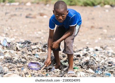 Hungry African Boy Rummaging Through A Pile Of Trash Looking For Something Recyclable Or Edible; Concept Of Extreme Childhood Poverty And Neglect