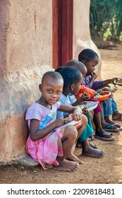 Hungry African Children Eating Porridge In Front Of The House In The Village