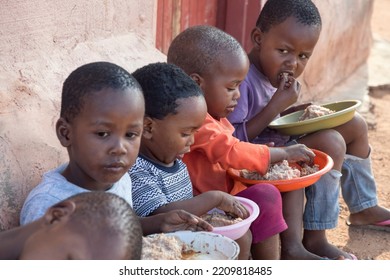 Hungry African Children Eating Porridge In Front Of The House In The Village