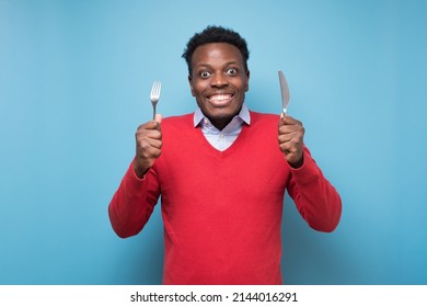 Hungry african young man holding fork and knife on hand ready to eat being excited.Diet and healthy food concept. - Shutterstock ID 2144016291