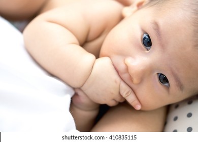 Hungry Asian Baby Sucking His Fingers Instead Of Mother Breastfeeding