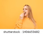 Hungry attractive girl eats a lot of French fries, holds a handful of snacks and puts it in the mouth. Close-up portrait of a girl greedily eats French fries on a yellow background