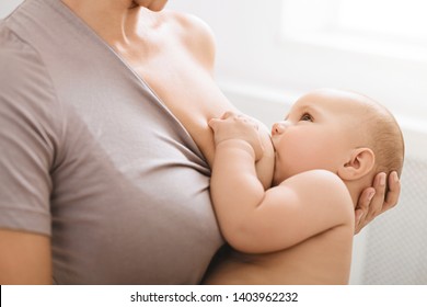 Hungry baby eating breast milk and looking at mom