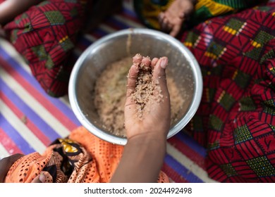 Hungry Black African Girl's Hand Is Taking A Serving Of Cereals Out Of A Metal Plate Shared With Other Family Members; Food Shortage Concept