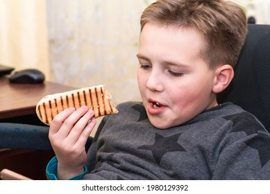 A Hungry Boy Eating A Hot Dog At Home Kid Eats A Hot-dog Sandwich.Indoors Shot.Closeup.