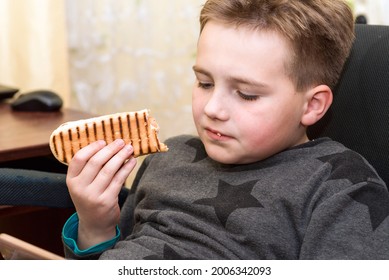 A Hungry Boy Eating A Hot Dog At Home Kid Eats A Hot-dog Sandwich.Indoors Shot.Closeup.