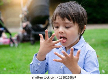 Hungry Boy Licking Snack From His Fingers, Acrive Child  Having Fun Eating Picnic In The Park, Kid Lick Fingers, Outdoor Outing Activity For Family On Weekend In Spring Or Summer.