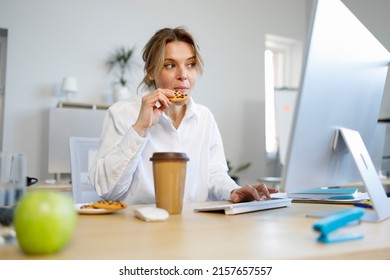 Hungry businesswoman office worker snacking on cookies while working on computer - Powered by Shutterstock