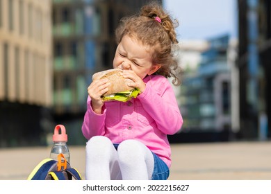 hungry cute girl, schoolgirl with appetite eating homemade sandwich between classes on campus outdoor. back to school child lunch. unhealthy, harmful and healthy food, snack for kid. children o - Powered by Shutterstock