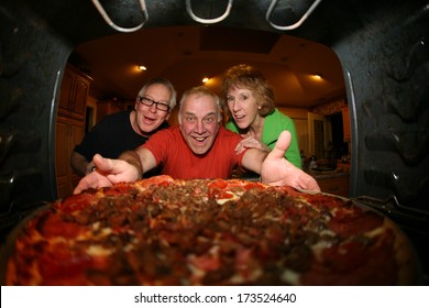 A Hungry And Excited Family Pull A Fresh Baked Pizza Out Of Their Oven For Dinner. Pizza Night.  Shot From The Inside Of The Oven Facing Out Showing A Unique View Not Often Seen. 