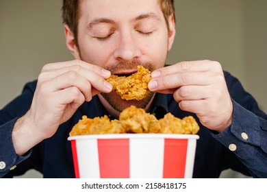 Hungry Excited Guy Eating Fried Chicken Wings. Caucasian Man Enjoying Junk Food.