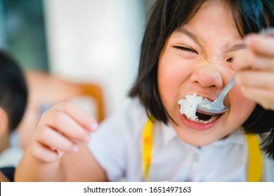 Hungry Face And Enjoy Eating Concept.Little Asian Girl Enjoy Eating With Rice And Vegetable On A Plate In Lunch Time At Home.Asian Kid Girl Holding Spoon With White Rice And Open Her Mouth.