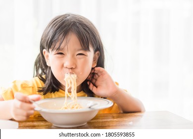 Hungry Face And Enjoy Eating Concept.Little Asian Girl Enjoy Eating With Spaghetti Carbonara With Cheese On A Plate In Lunch Time At Restaurant.kid Eating Pasta.Delivery Food, Delicious Face.