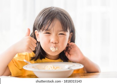 Hungry Face And Enjoy Eating Concept.Little Asian Girl Enjoy Eating With Spaghetti Carbonara With Cheese On A Plate In Lunch Time At Restaurant.kid Eating Pasta.Delivery Food, Delicious Face.