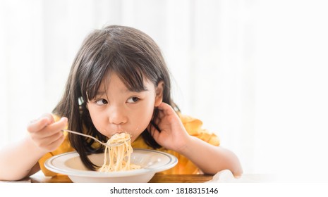 Hungry Face And Enjoy Eating Concept.Little Asian Girl Enjoy Eating With Spaghetti Carbonara With Cheese On A Plate In Lunch Time At Restaurant.kid Eating Pasta.Delivery Food, Delicious Face.